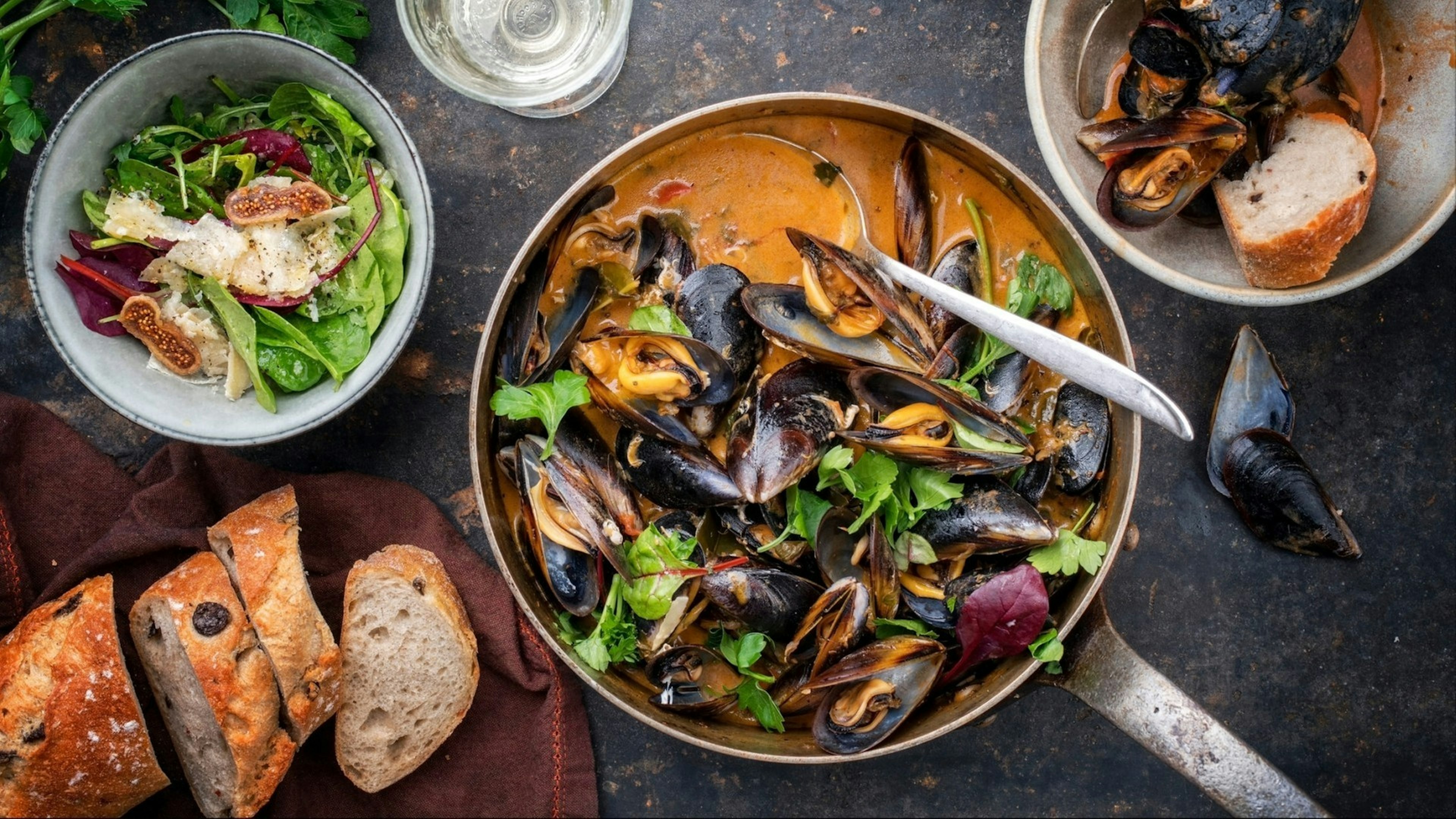 Traditional French blue mussel in bouillabaisse with lettuce and baguette as top view in a casserole