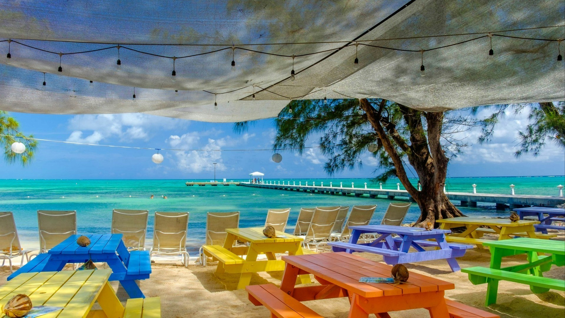 View of the Caribbean Sea from wooden colored tables on the beach at Rum Point