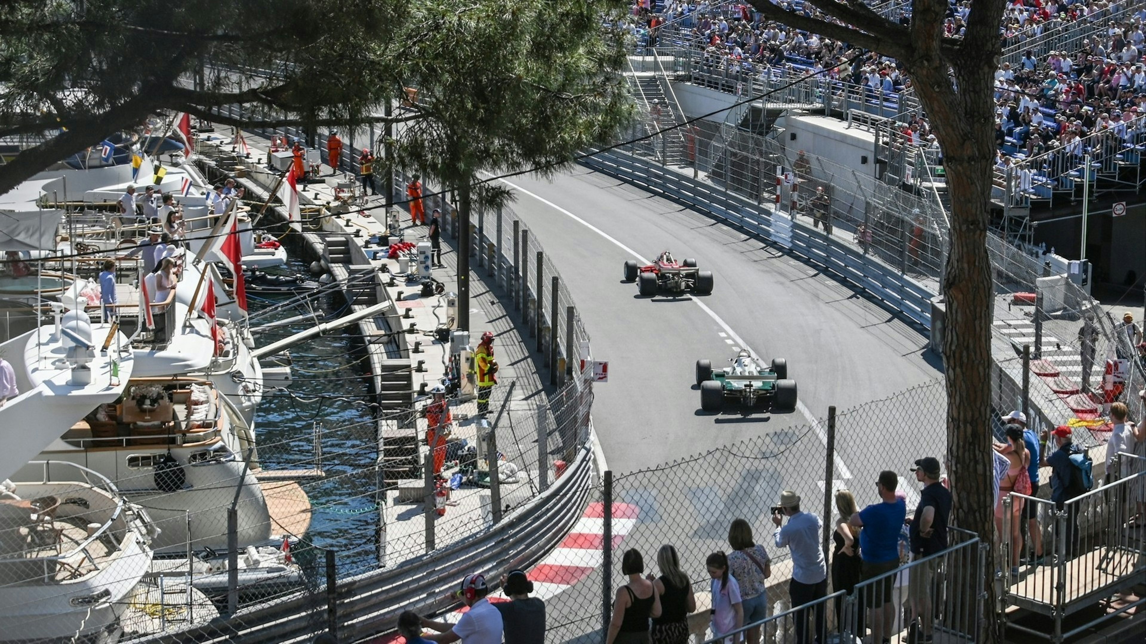 Yachts in the harbor, fans in the stands, and cars on the track at the Monaco Historic Grand Prix