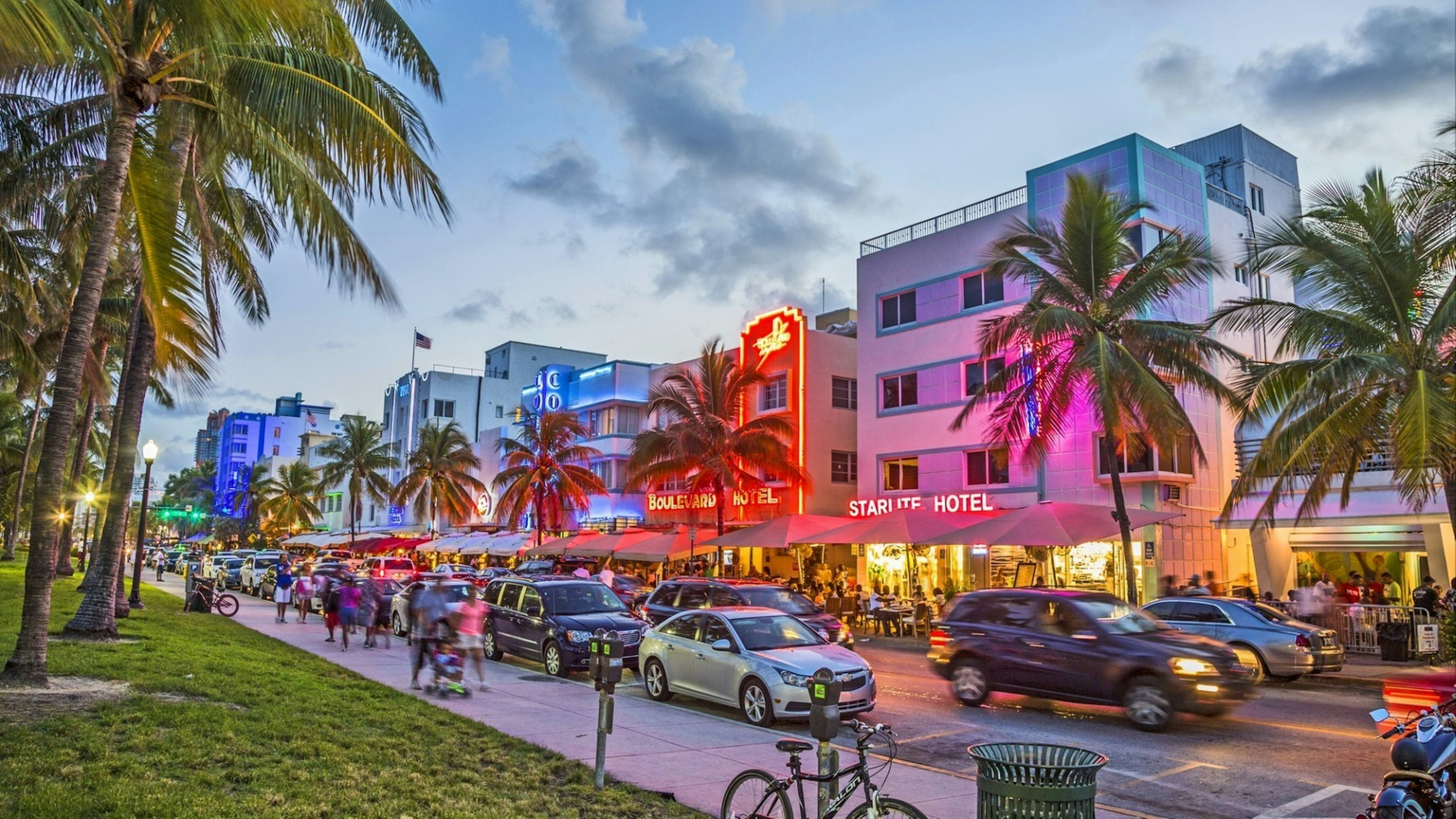 People enjoy Palm trees and art deco hotels at Ocean Drive by night