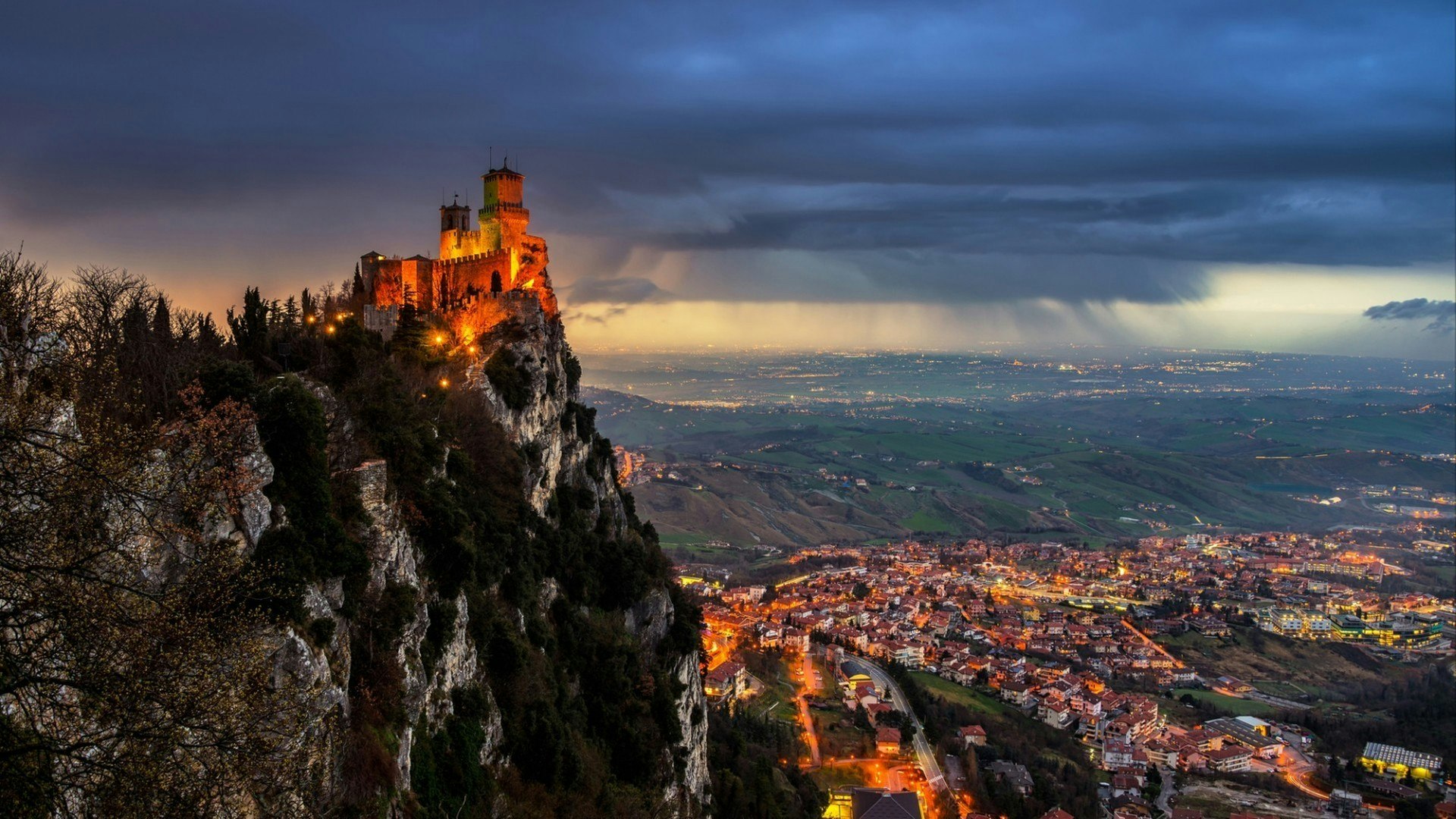San Marino fortress of Guaita on Mount Titano at sunset. Heavy raining clouds with aerial view at the city